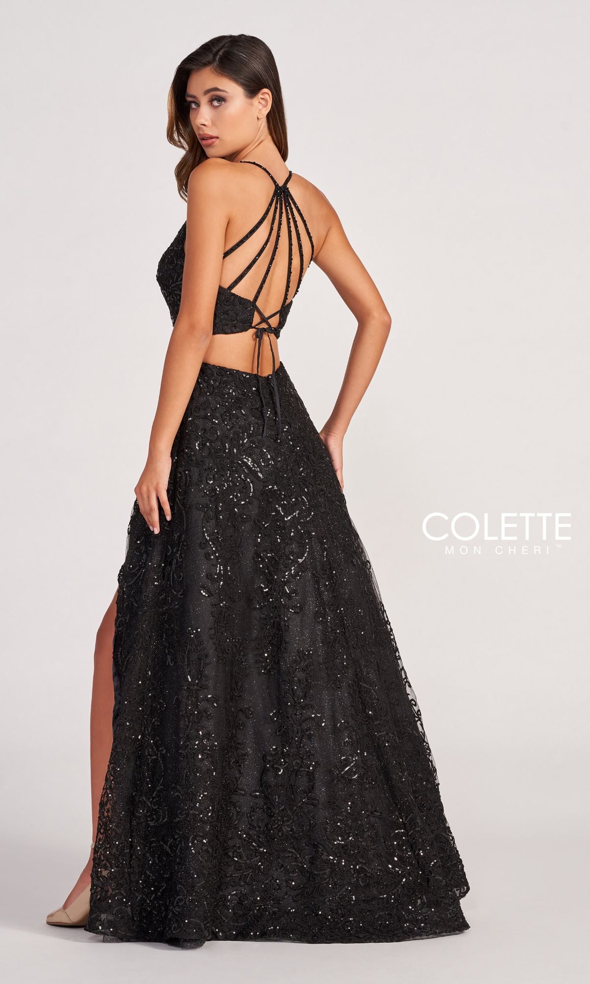 Woman wearing the Colette CL2028 Strappy-Back Lace A-Line Prom Dress featuring a long, black silhouette with sequins, open back, strappy details, and side slit. The COLETTE Mon Cheri logo appears in the bottom right corner.